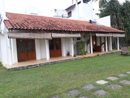 a white house with a red roof and a yard at Muthumuni Ayurveda Beach Resort in Beruwala