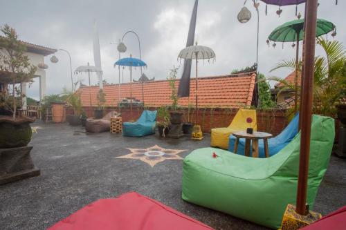 a patio with umbrellas and chairs and a table at Poshtel Ubud in Ubud