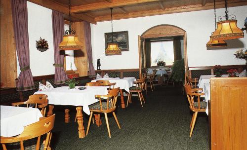 a dining room with white tables and wooden chairs at Gästehaus Pfatischer Hotel Fewo in Rottach-Egern