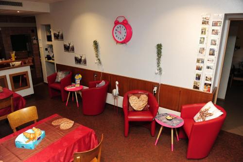 a restaurant with red chairs and tables and a clock at Hotel Restaurant Au Chasseur in Orbe
