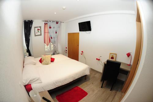 a small bedroom with a white bed and a red rug at Hotel Restaurant Au Chasseur in Orbe