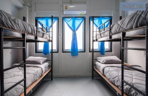 two bunk beds in a room with blue curtains at Zee Thai Hostel in Bangkok
