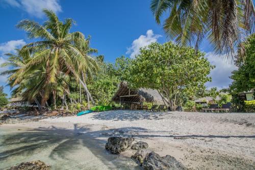 a sandy beach with palm trees and a resort at Le Coconut Lodge in Avatoru