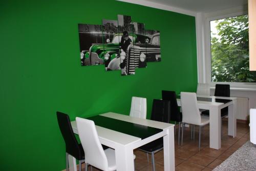 a green dining room with a white table and white chairs at Ahoi-Gästehaus in Hamburg