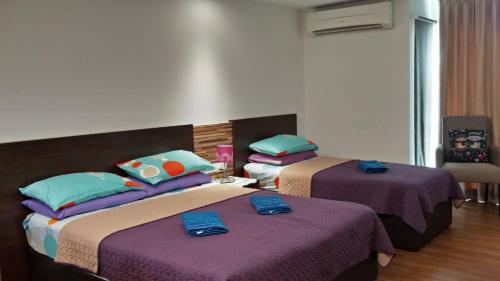 two beds in a room with purple and blue at Mama Studio Inn in Kota Bharu