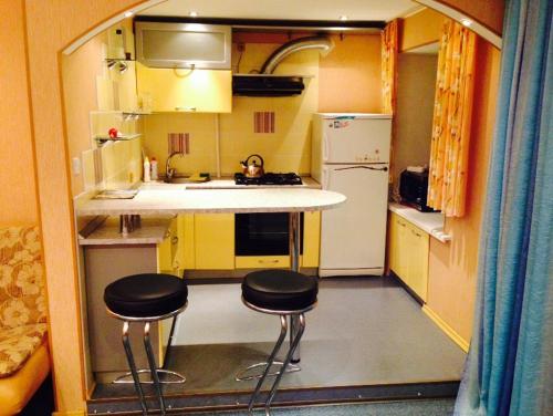 a small kitchen with two stools in the middle of it at Apartment on Druzhby 4 in Perm