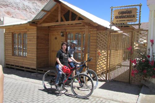 Codpa的住宿－Cabañas Turísticas Guañacagua - Valle de Codpa，两个人坐在一辆自行车上,在一座建筑前