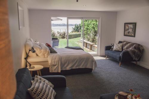 een slaapkamer met een bed, een bank en een raam bij Water & City Lights Studio in Tauranga