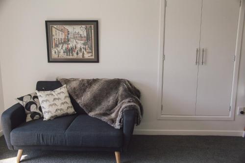 a living room with a blue couch with a blanket at Water & City Lights Studio in Tauranga