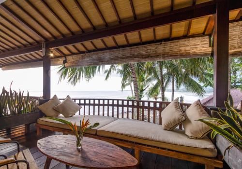 a couch on a porch with a view of the ocean at Bombora Medewi in Pulukan