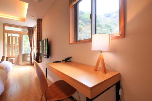 a room with a desk with a lamp and windows at Hotel Okada in Hakone