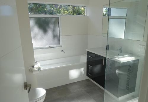 a bathroom with a tub and a toilet and a sink at The Villa Dunsborough in Dunsborough