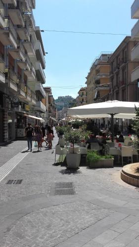 una calle de la ciudad con mesas y sombrillas blancas en Le Sculture B&B, en Cosenza