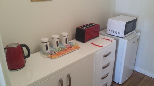 a white counter with a microwave and a coffee maker at Alexander Drive B & B in Esperance