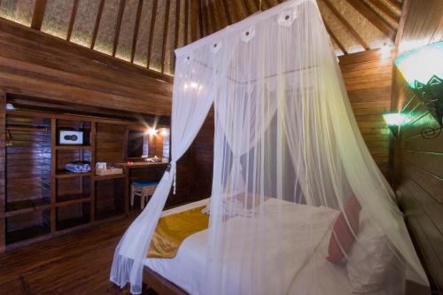 a bedroom with a bed with a mosquito net at Amora Hut's in Nusa Lembongan