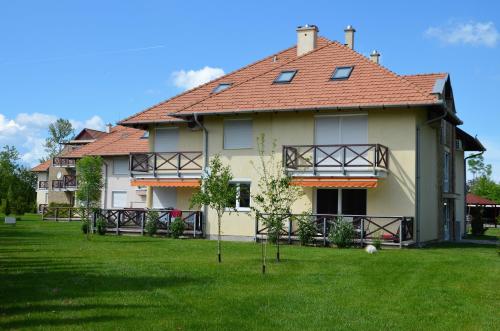 a large house with a red roof on a green field at Vadszilva Apartman in Balatonőszöd