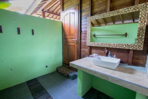 La salle de bains est pourvue d'un lavabo et d'un miroir. dans l'établissement Amora Hut's, à Nusa Lembongan