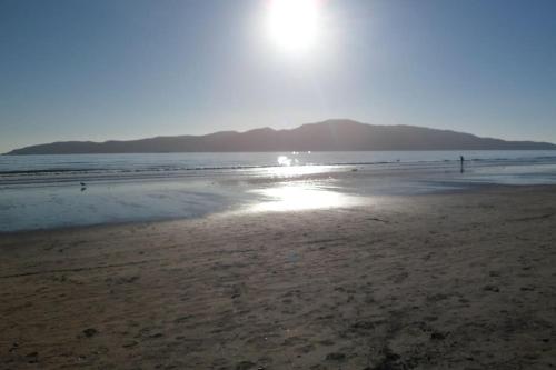 a beach with the sun shining on the water at Dream Escape for 2 in Paraparaumu Beach