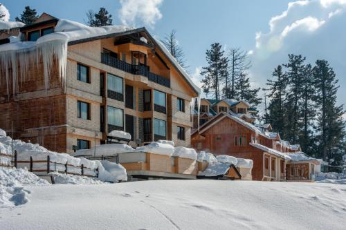 a building covered in snow next to a snow covered yard at The Vintage Gulmarg in Gulmarg