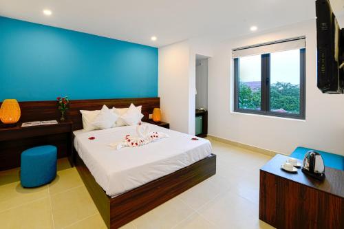 a bedroom with a large bed with a blue wall at Hoi An Dream City Hotel in Hoi An