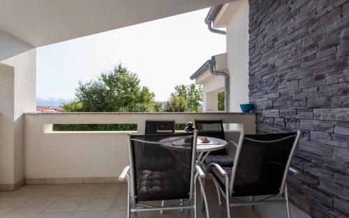 a patio with a table and chairs and a brick wall at Apartments Matea in Baška