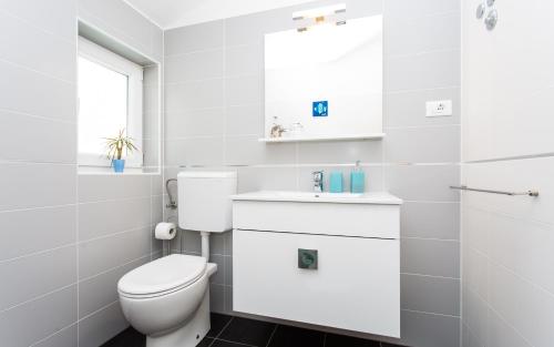 a white bathroom with a toilet and a sink at Apartments Matea in Baška