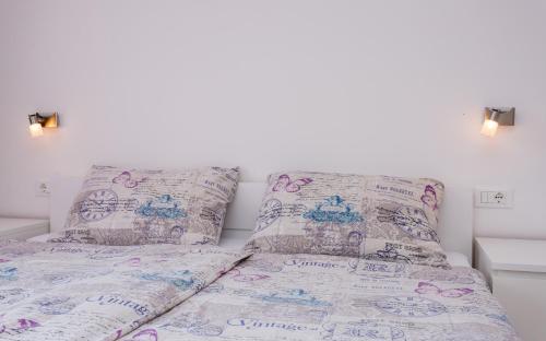 a bed with a comforter and two pillows at Apartments Matea in Baška