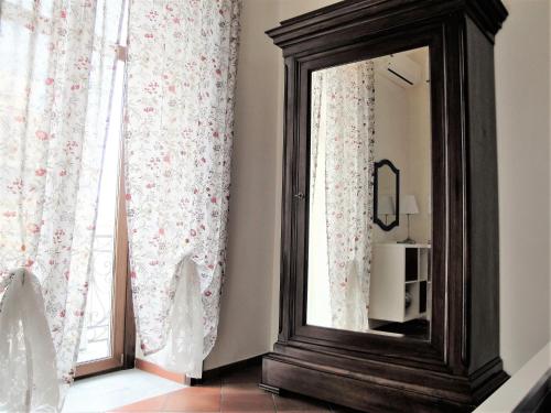 a mirror sitting next to a window with curtains at Umberto I Holiday House in Naples