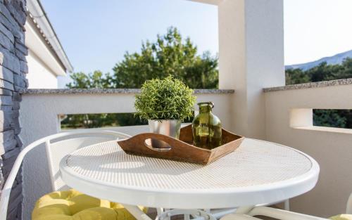a table with a bottle and a plant on a balcony at Apartments Matea in Baška