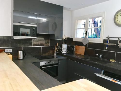 une cuisine avec comptoirs noirs et une horloge murale dans l'établissement Villa Olivea, à Rayol-Canadel-sur-Mer