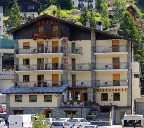 a hotel on a mountain with cars parked in front of it at Hotel Bijou in Valtournenche