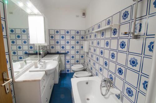 - une salle de bains bleue et blanche avec deux lavabos et des toilettes dans l'établissement Appartamenti Katinanna, à Alleghe