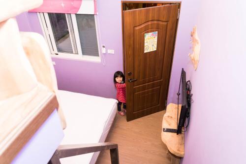 een klein meisje dat bij de deur van een kamer staat bij Clover B&B in Yuchi