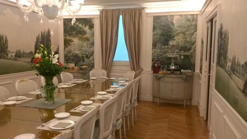 una sala da pranzo con un lungo tavolo e sedie bianche di Villa Vitae a Castiglione Falletto