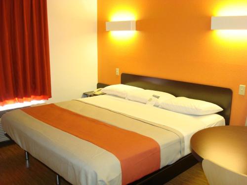 a bedroom with a large bed with orange walls at Motel 6-Arkadelphia, AR in Arkadelphia