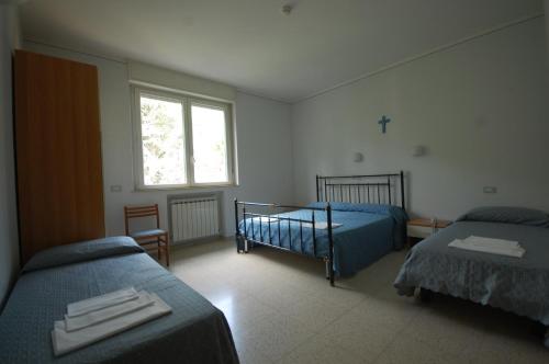 a bedroom with two beds and a cross on the wall at Casa Religiosa Di Ospitalità Nazareno in Spoleto