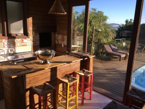 uma cozinha com um balcão e bancos em frente a um deque em Condomínio Varandas da Lagoa na Praia do Rosa