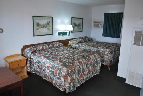 ein Hotelzimmer mit 2 Betten und einem Tisch in der Unterkunft Plaza Inn in Great Falls