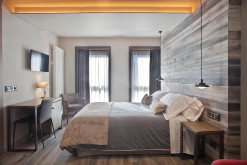 Un dormitorio con una cama grande y un escritorio con un escritorio. en Hotel Boutique La Neu en Benasque