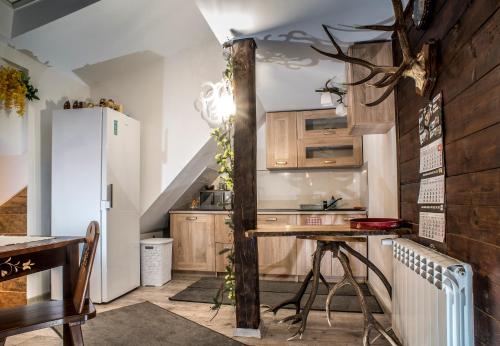 Una cocina con gabinetes de madera y un refrigerador blanco. en Apartamenty Góraleczka z widokiem- pokój zabaw, en Czarna Góra