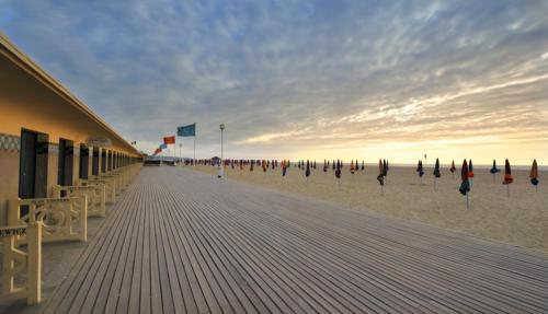 a wooden boardwalk with umbrellas on the beach at Les marinas vue Mer in Deauville
