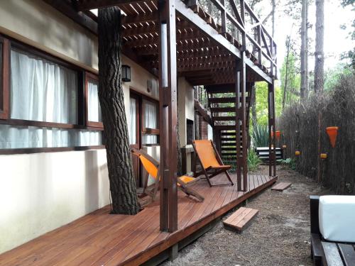 une maison dotée d'une terrasse en bois avec deux chaises dans l'établissement La Hora del Sol Apart, à Mar de las Pampas