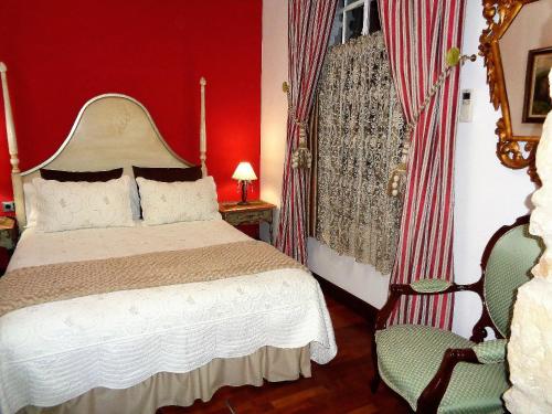 a red bedroom with a bed and a chair at Hotel Boutique Nueve Leyendas in Úbeda