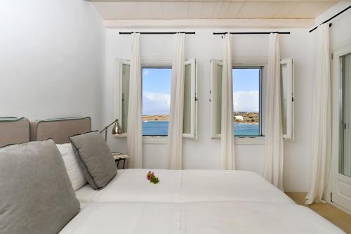 a white bedroom with a bed and two windows at Kalypso Villas in Naousa