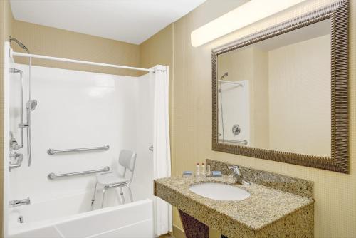 a bathroom with a sink and a tub and a mirror at Wingate by Wyndham Atlanta Fairburn in Fairburn