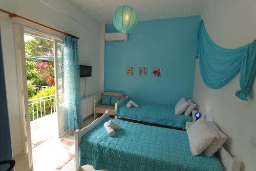 1 dormitorio azul con 2 camas y ventana en Angeliki Studio and Apartment en Gaios