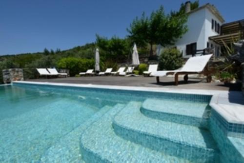 a swimming pool with blue water and white chairs at Esperos Suites & Villas in Lafkos