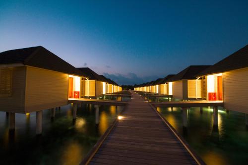 a row of houses on the water at night at Summer Island Maldives in North Male Atoll