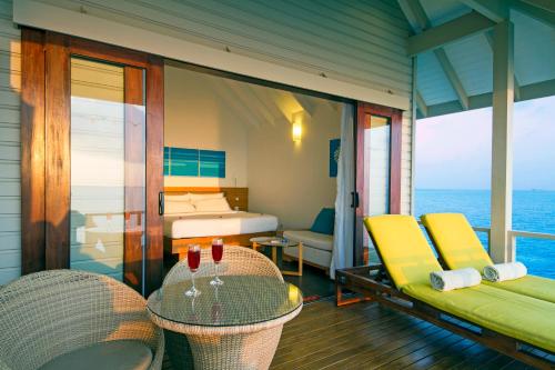 a room with a balcony with a bed and a table and chairs at Summer Island Maldives in North Male Atoll