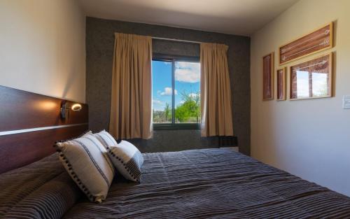 a bedroom with a bed with pillows and a window at Casas Acrux in Nono